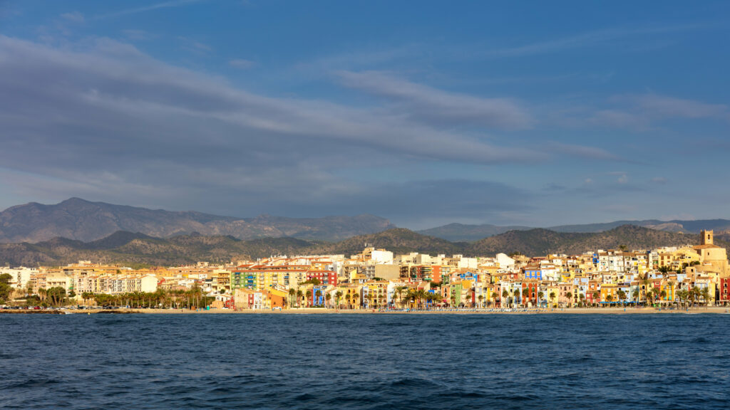 Vibrant Coastal Cityscape Wallpaper with Mountains and Calm Sea