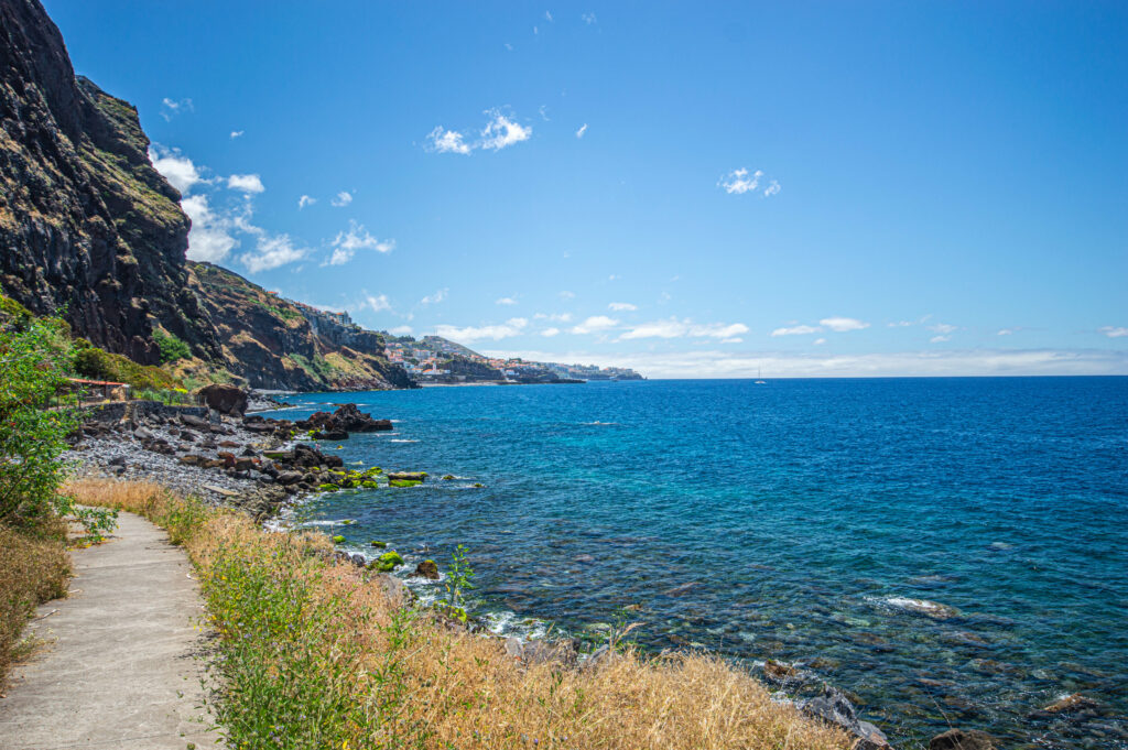Coastal landscape wallpaper with clear blue sea rugged rocks greenery steep cliffs vivid sky