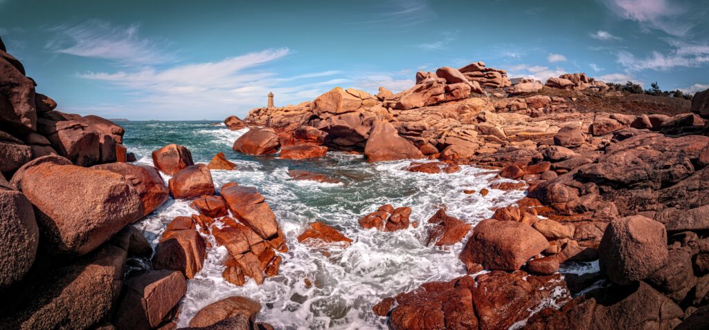 Vibrant coastal landscape with rugged red rocks and dynamic sea waves under bright blue sky wallpaper