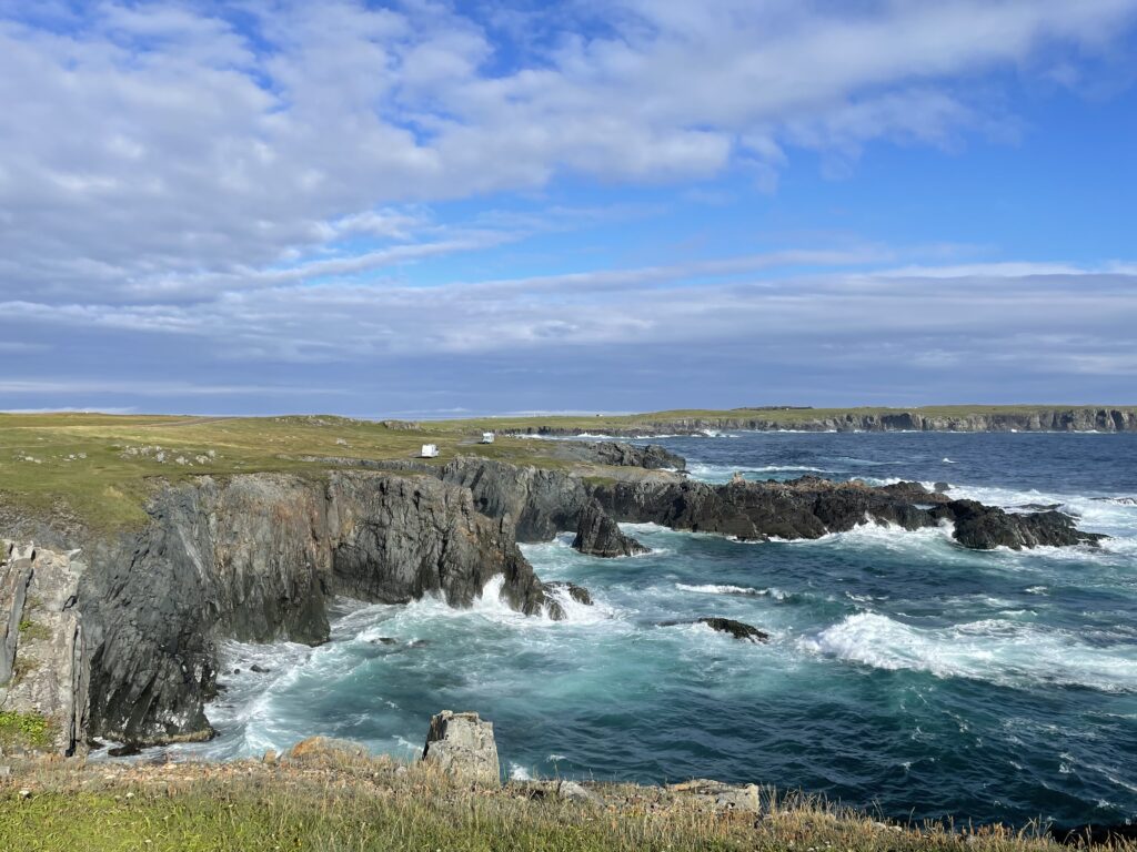 Vibrant coastal landscape with rugged rocks crashing waves lush green cliffs and turquoise sea Wallpaper