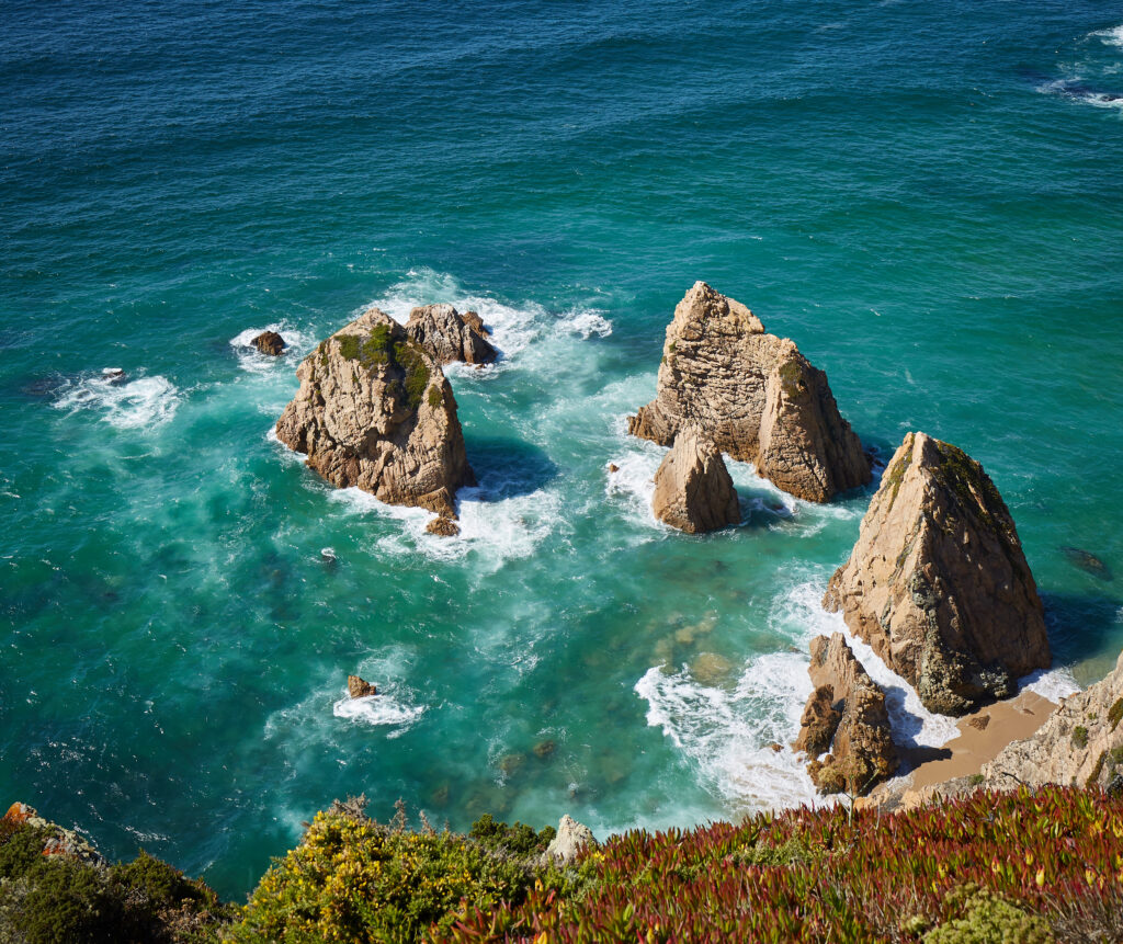 Vibrant coastal wallpaper with turquoise waves crashing on rugged cliffs and lush green shoreline