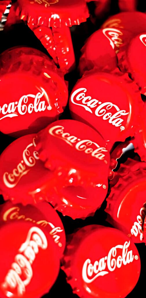 Close-up of bright red Coca-Cola bottle caps with iconic white logo vibrant wallpaper background