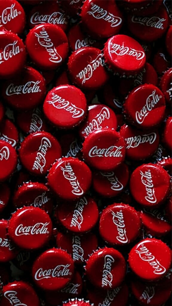 Vibrant Coca Cola wallpaper with glossy red bottle caps and classic white logo pattern background