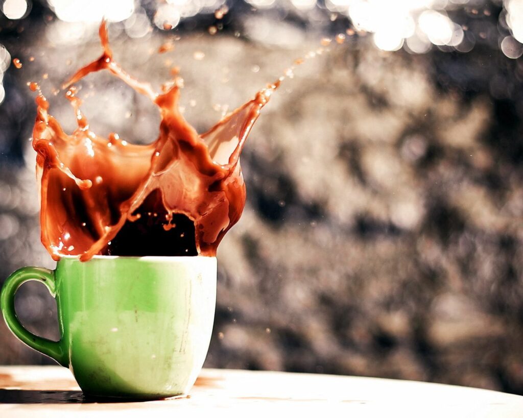 Dynamic Coffee Splash Wallpaper: Vibrant Green Cup Background Art