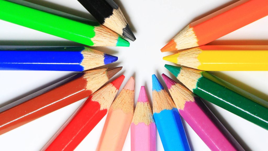 Colorful sharpened pencils arranged in a vibrant radial circle on white minimalist background Wallpaper