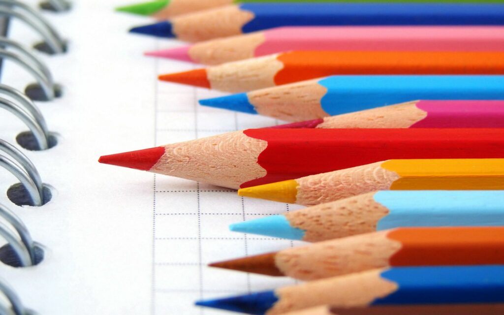 Vivid Colored Pencils on Gridded Notebook: Creative Wallpaper Background