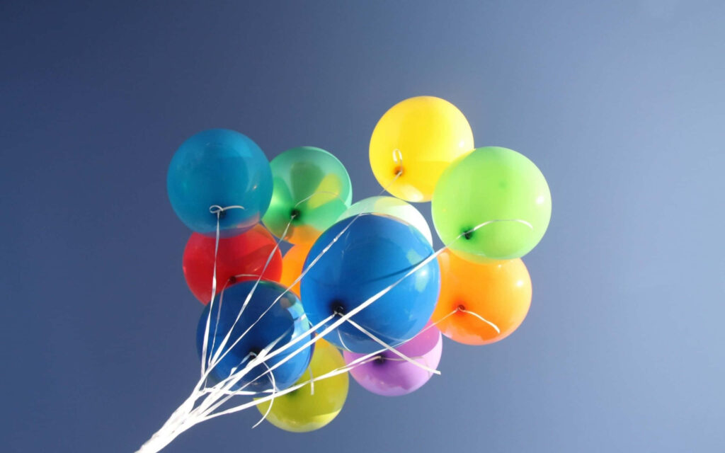 Colorful balloons cluster floating against clear blue sky vibrant uplifting wallpaper background