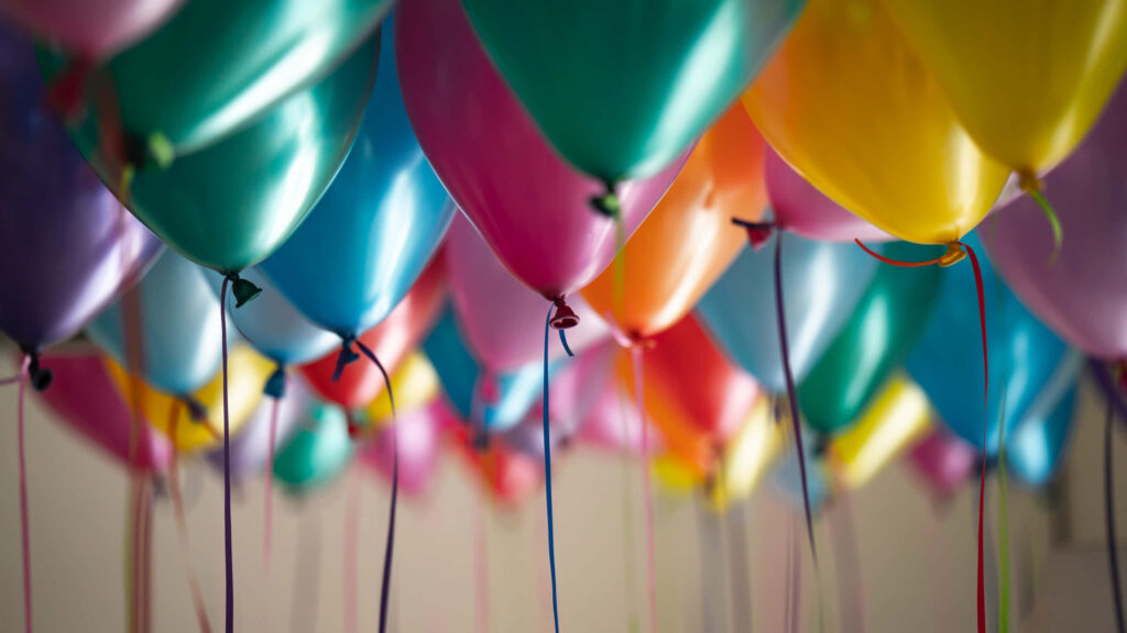 Colorful balloons hanging from ceiling creating festive cheerful vibrant party wallpaper background