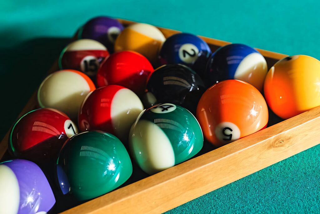Colorful billiard balls arranged in triangle rack on green pool table with vibrant lighting Wallpaper
