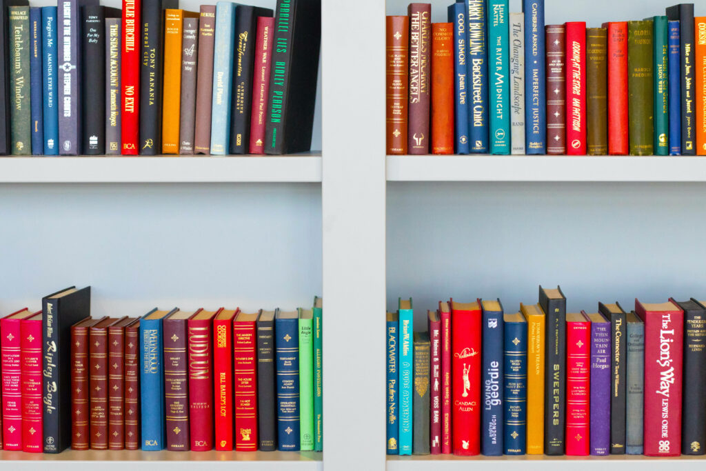 Colorful books neatly arranged on white shelves vibrant library wallpaper background design