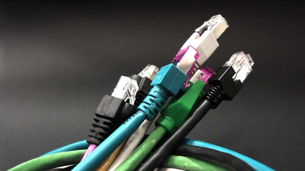 Close-up of colorful Ethernet cables with clear connectors on dark gradient technical wallpaper background