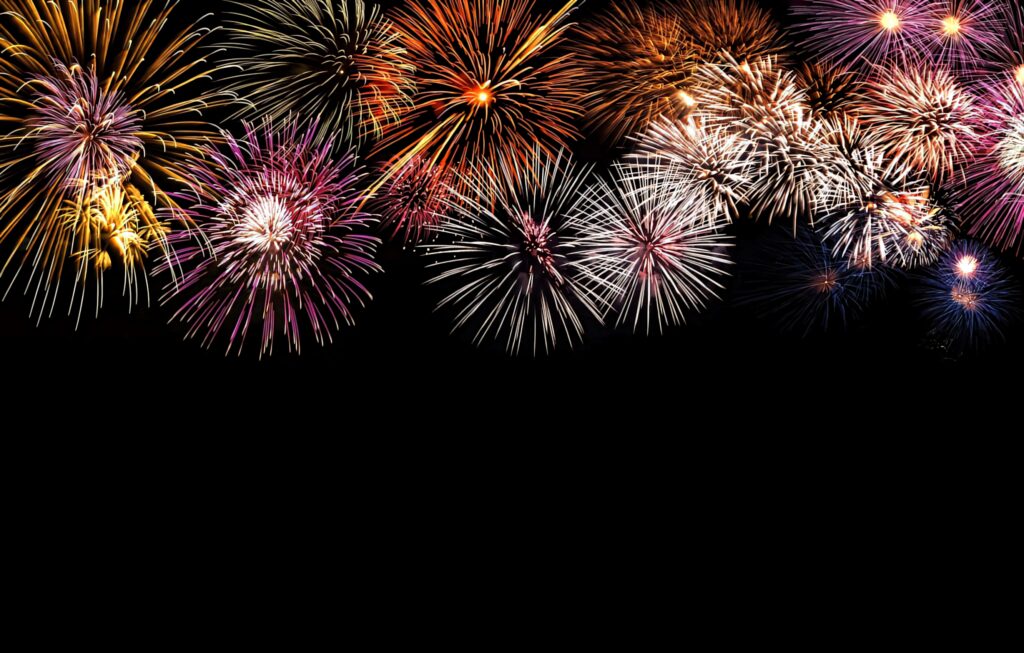 Colorful fireworks burst brightly on a black background creating a festive celebration wallpaper