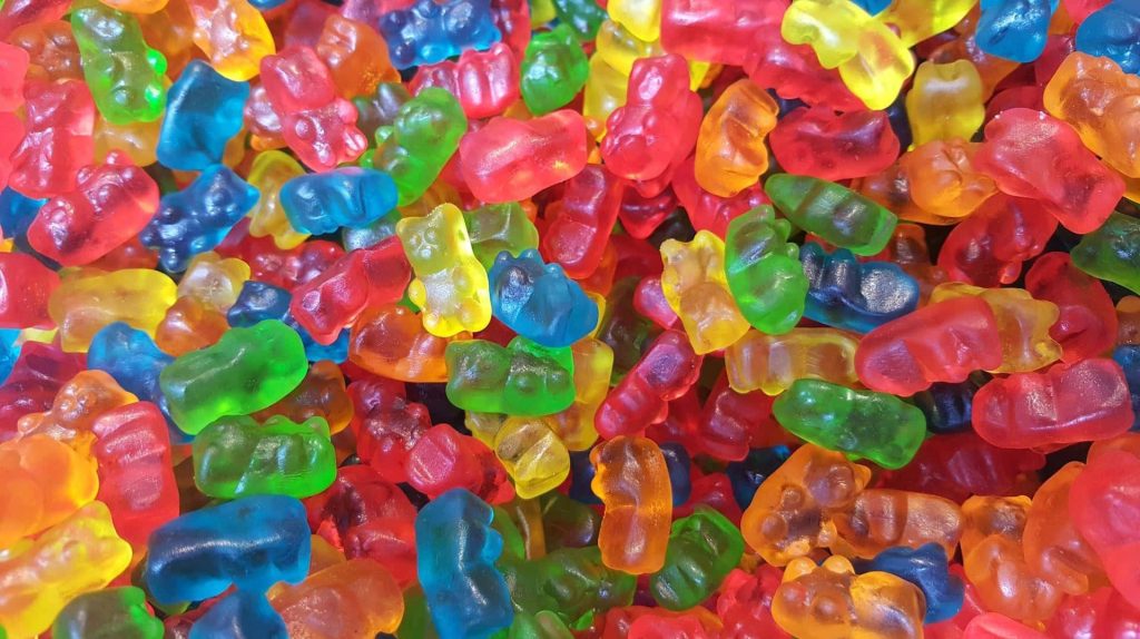 Close-up vibrant colorful gummy bears pile with bright sugary translucent jelly candy texture wallpaper
