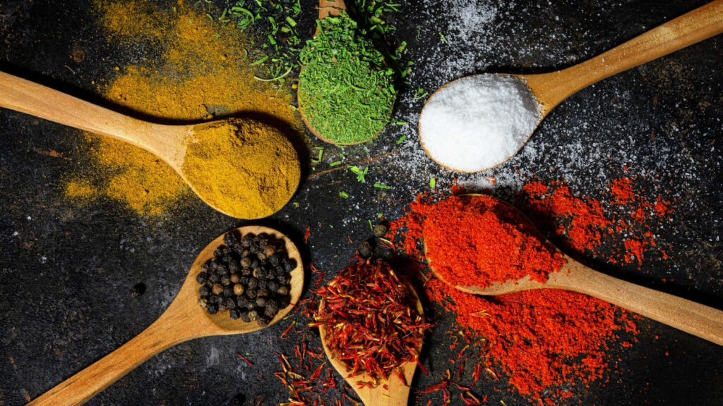 Vibrant Cooking Spices on Wooden Spoons - Culinary Beauty Wallpaper