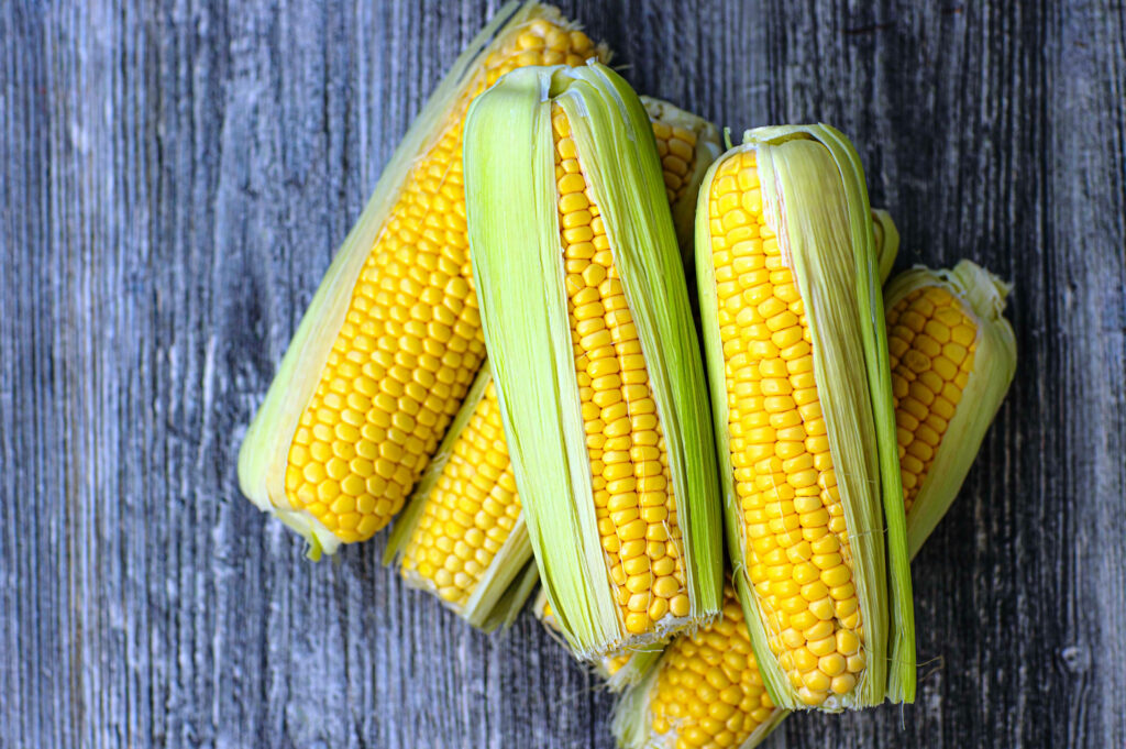 Vibrant Corn Wallpaper: Fresh Green Kernels on Rustic Wood Background