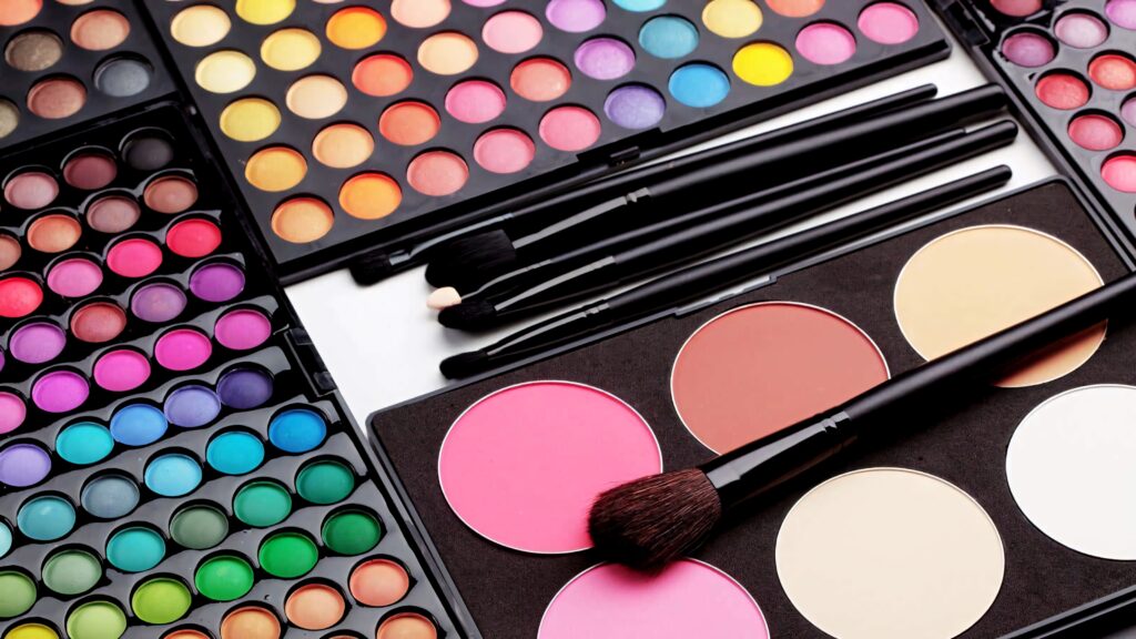 Colorful eyeshadow palettes blushes and makeup brushes arranged in vibrant modern cosmetics wallpaper