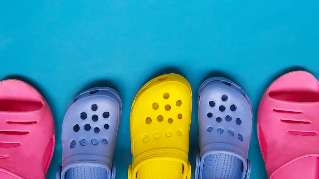 Colorful pink blue and yellow Crocs lineup on turquoise background vibrant footwear wallpaper