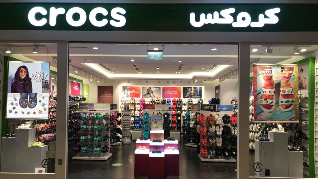 Bright Crocs Outlet Store interior with colorful footwear on racks and bilingual branding signage Wallpaper