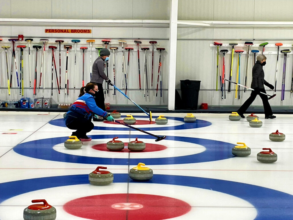 Vibrant Curling Practice Wallpaper: Players Focused on Sliding Stones