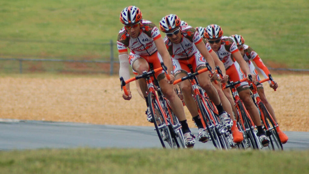 Dynamic Cyclists in Red & White Jerseys Racing Together - Wallpaper