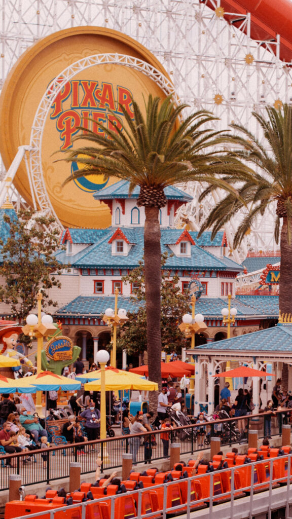 Vibrant Disneyland Pixar Pier wallpaper with colorful buildings palm trees and happy visitors