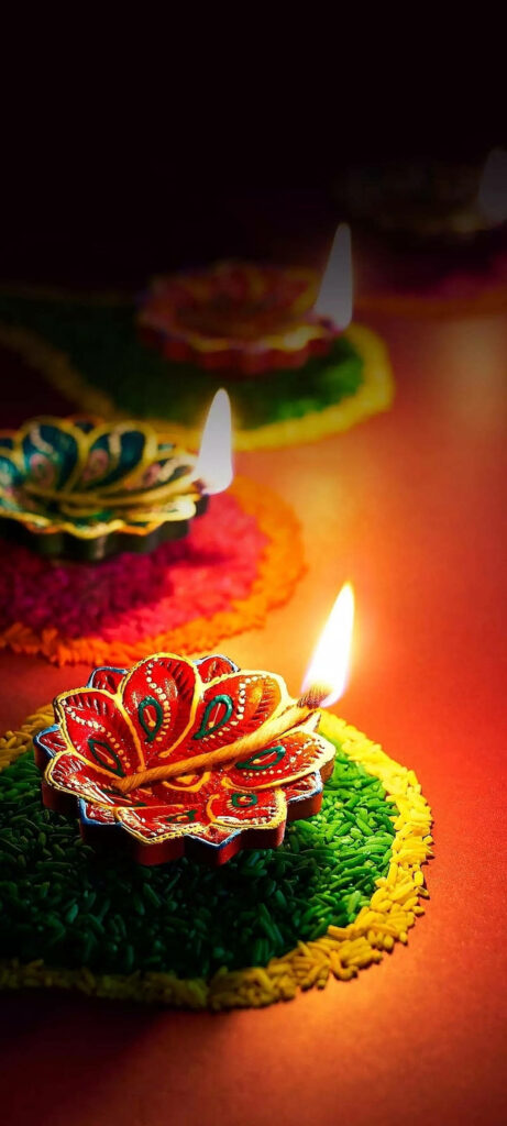 Vibrant Diwali oil lamps glowing on colorful rangoli with festive red yellow and green hues wallpaper