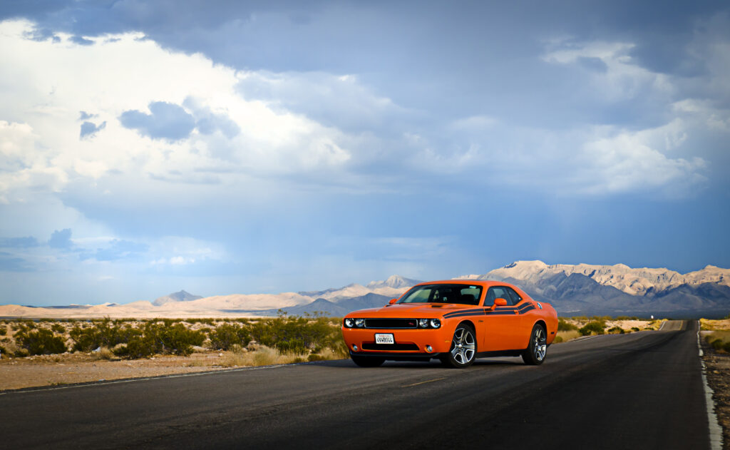 Vibrant Orange Dodge Challenger: Adventure on the Open Road Wallpaper