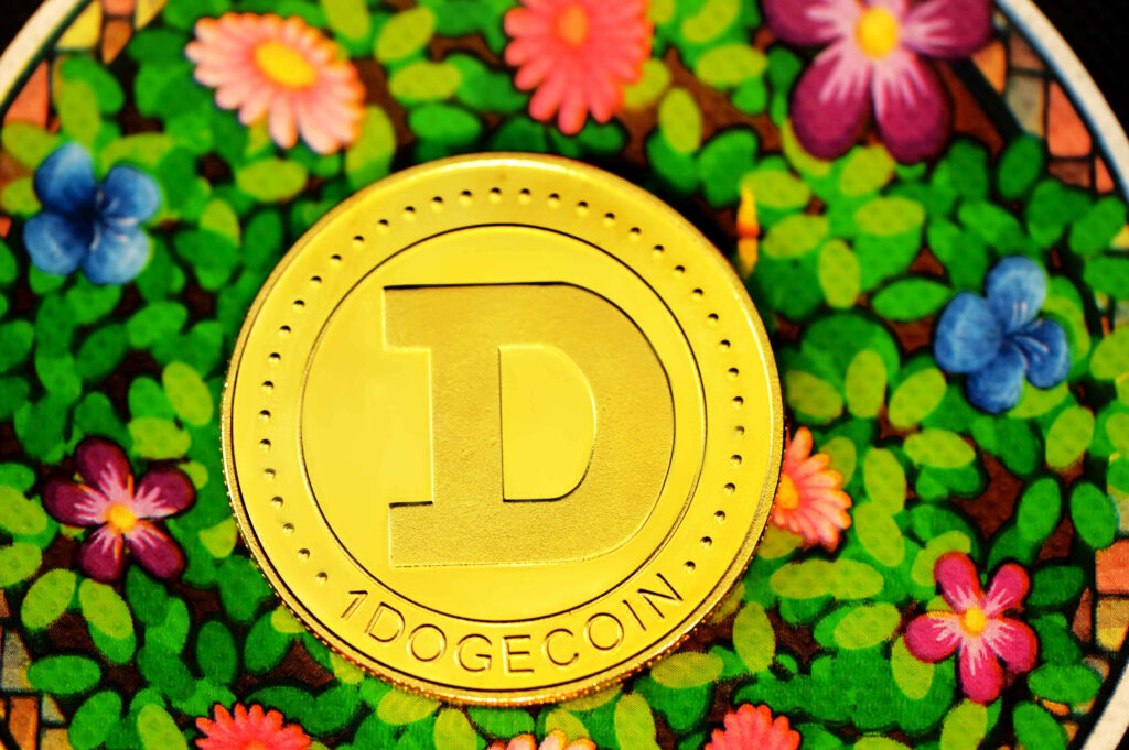 Golden Dogecoin coin centered on vibrant floral background with colorful flowers and green leaves Wallpaper