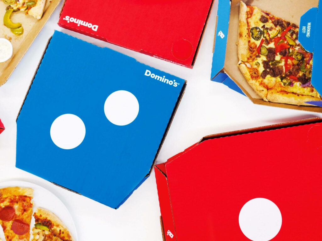Vibrant wallpaper with Domino's Pizza boxes and fresh slices in bold blue red and white design