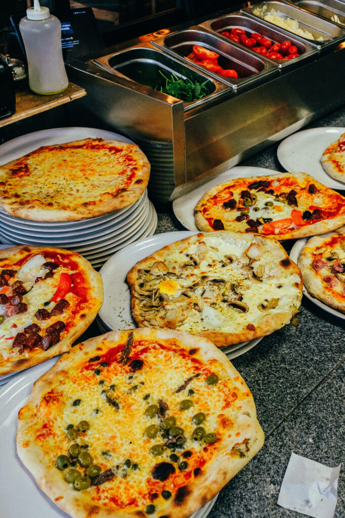 Freshly baked Domino's pizzas with varied toppings on white plates in a vibrant pizzeria kitchen Wallpaper