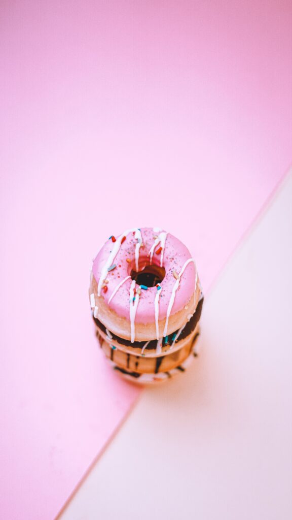 Colorful Donuts Wallpaper: Vibrant Frosted Treats on Pink Background