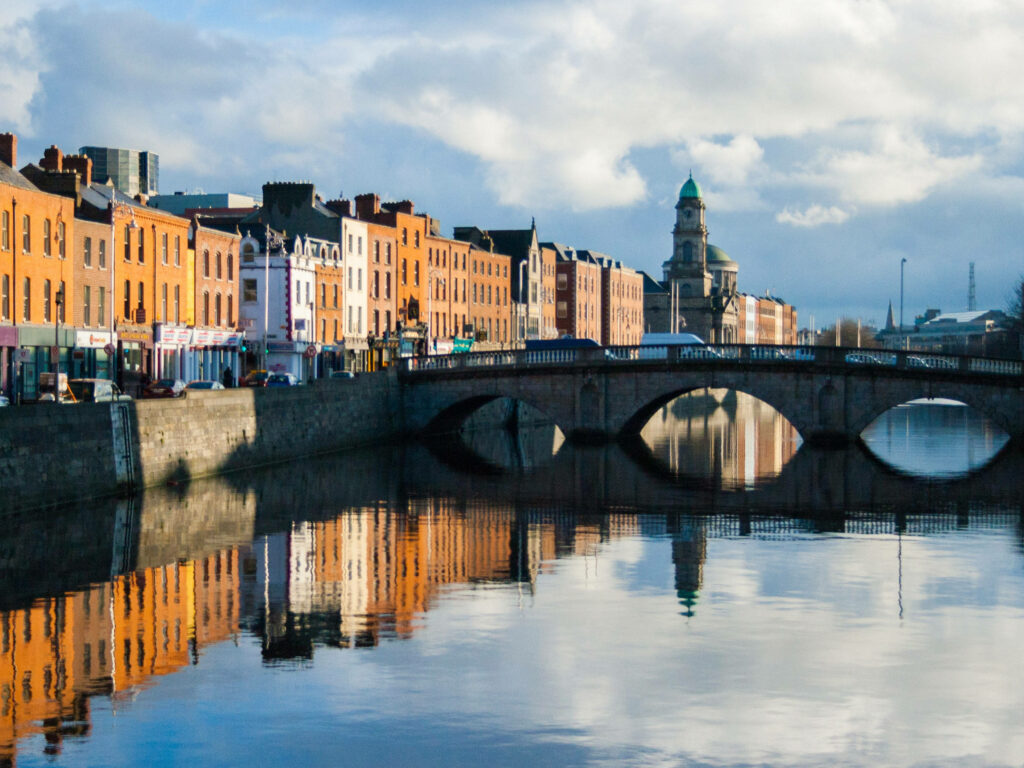Vibrant Dublin Mellows Bridge over River Liffey with colorful buildings reflecting in calm water Wallpaper