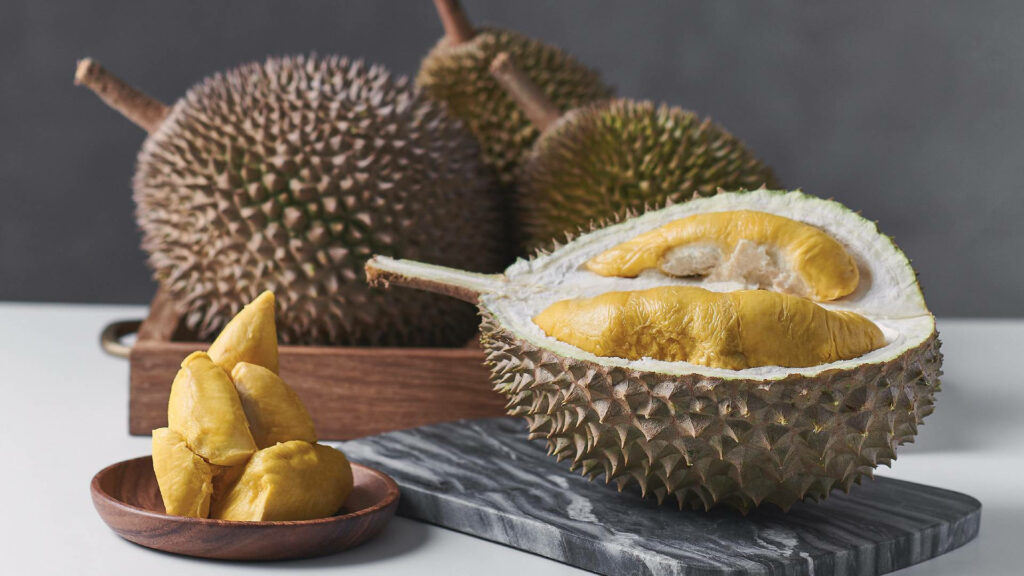 Vibrant Durian Wallpaper: Spiky Fruits & Golden Pulps on Table