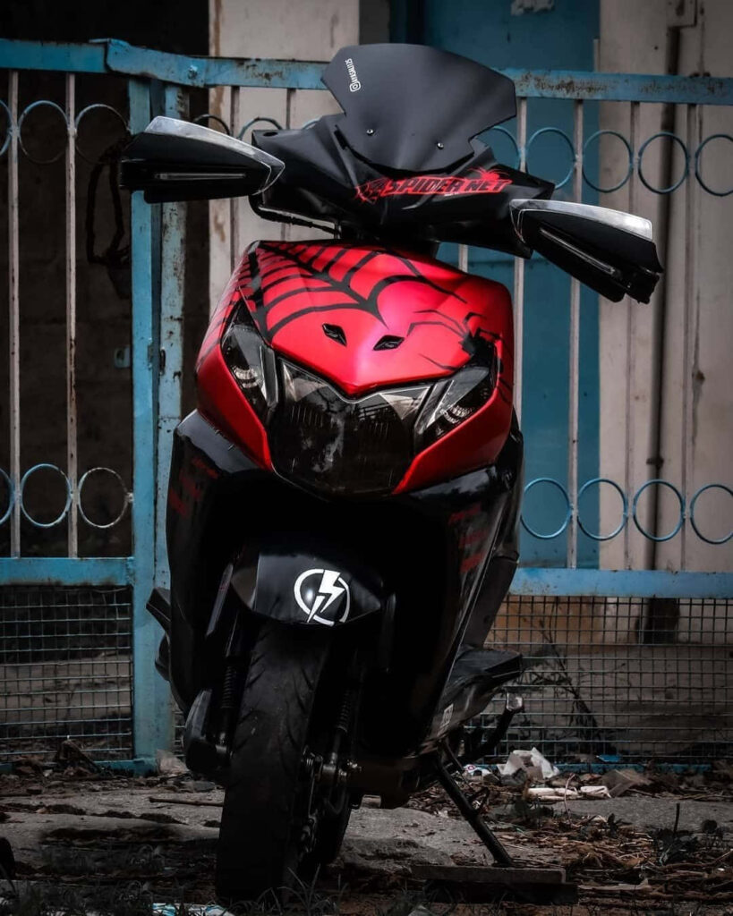 Spinning through the Streets: Captivating Dio Bike Front View with Red Chrome Finish, Spiderweb Sticker, and Matte Black Aesthetic - Motorcycle Photography Wallpaper