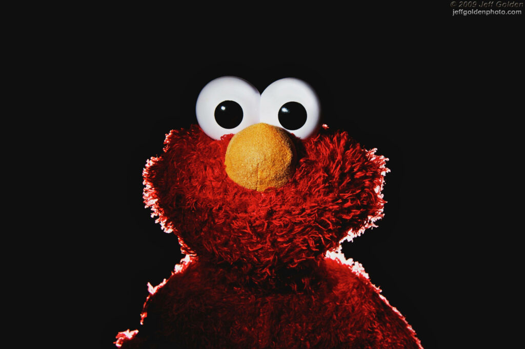 Elmo puppet with bright red fur and big white eyes on black background vivid character wallpaper