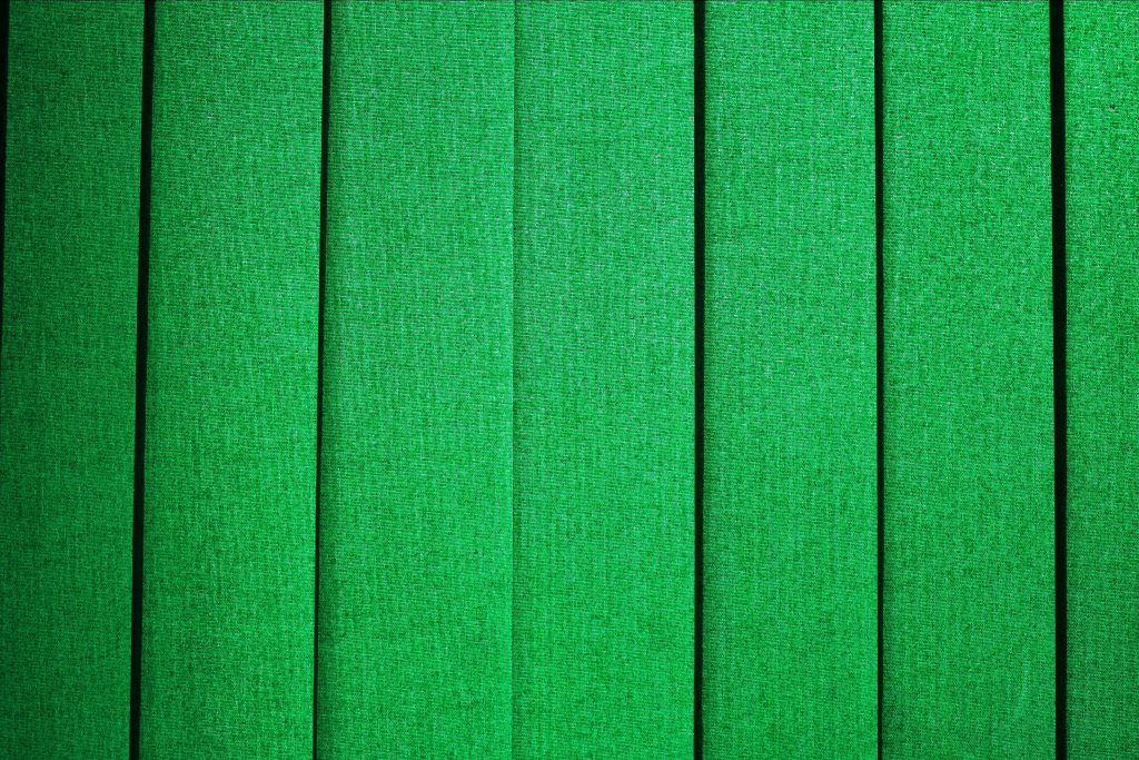Close-up of vibrant emerald green woven textile vertical blinds with modern minimalist design background Wallpaper