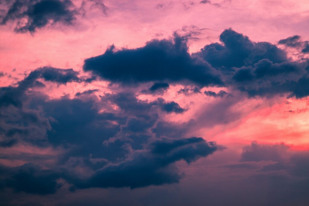 Dramatic evening sunset clouds in vibrant pink and deep blue sky tranquil wallpaper background