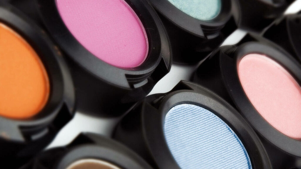 Close-up of vibrant colorful eyeshadow palettes in black containers showcasing makeup art and beauty Wallpaper