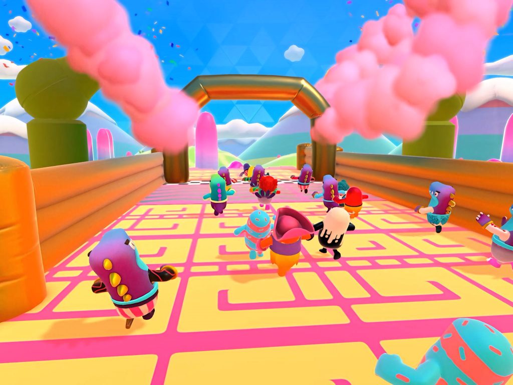 Fall Guys gameplay with colorful beans racing on pink yellow grid finishing at golden arch background Wallpaper