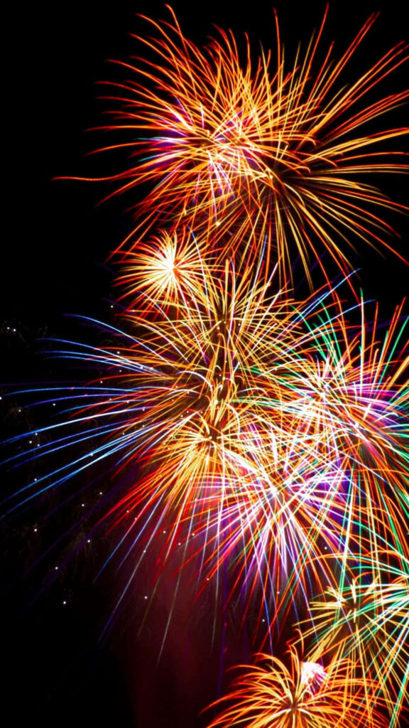 Vibrant colorful fireworks bursting in dark night sky wallpaper background for celebrations