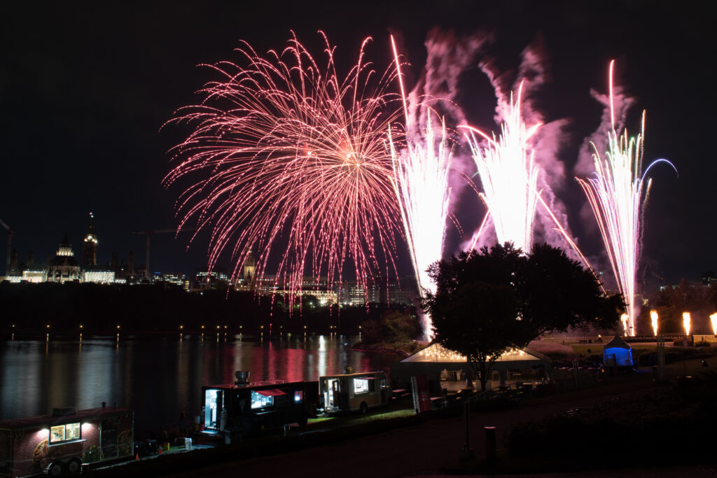 Vibrant Fireworks Riverside Celebration Wallpaper Background