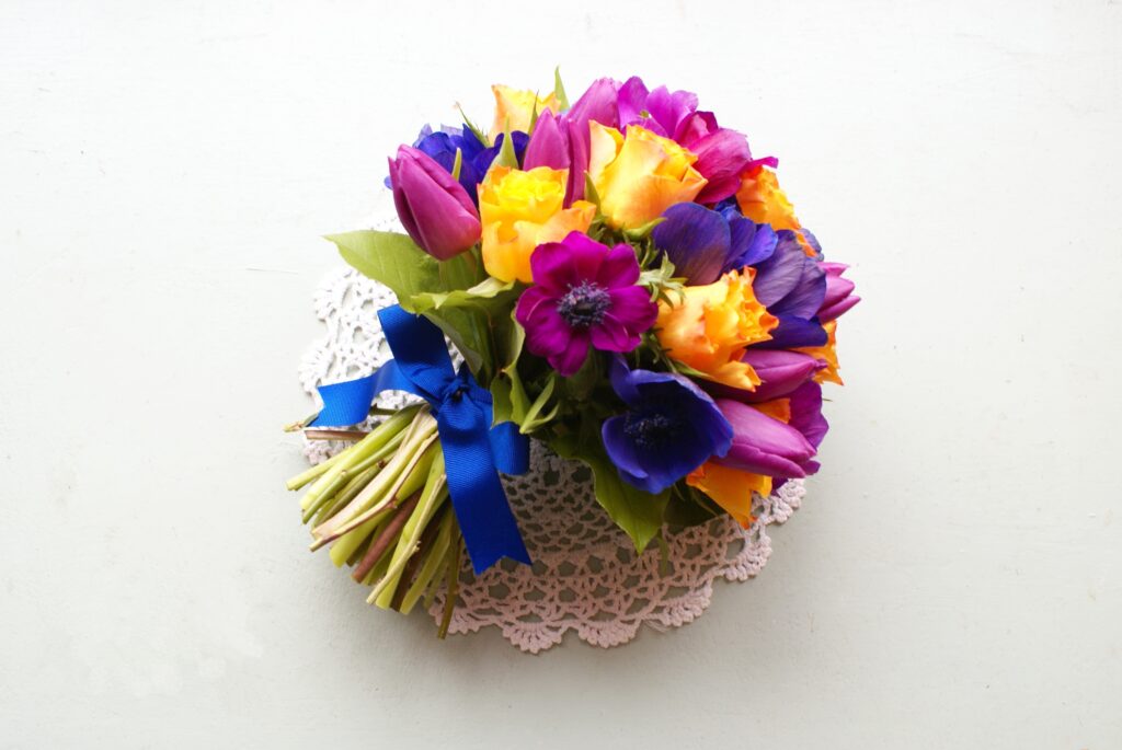 Vibrant Purple, Pink, and Yellow Flower Bouquet on Lace Doily Wallpaper
