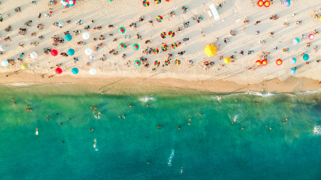 Aerial view of Florida beach with colorful umbrellas swimmers and clear turquoise water wallpaper