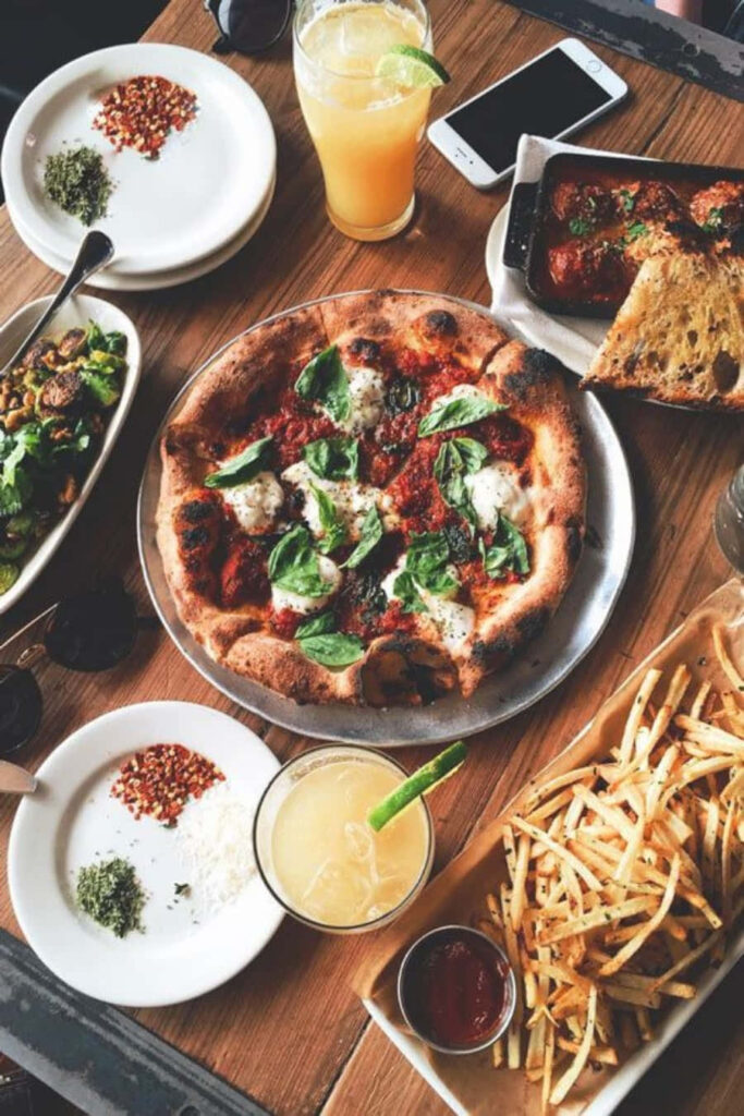 Vibrant Table Spread: Delicious Pizza, Fries & Refreshing Beverages Wallpaper