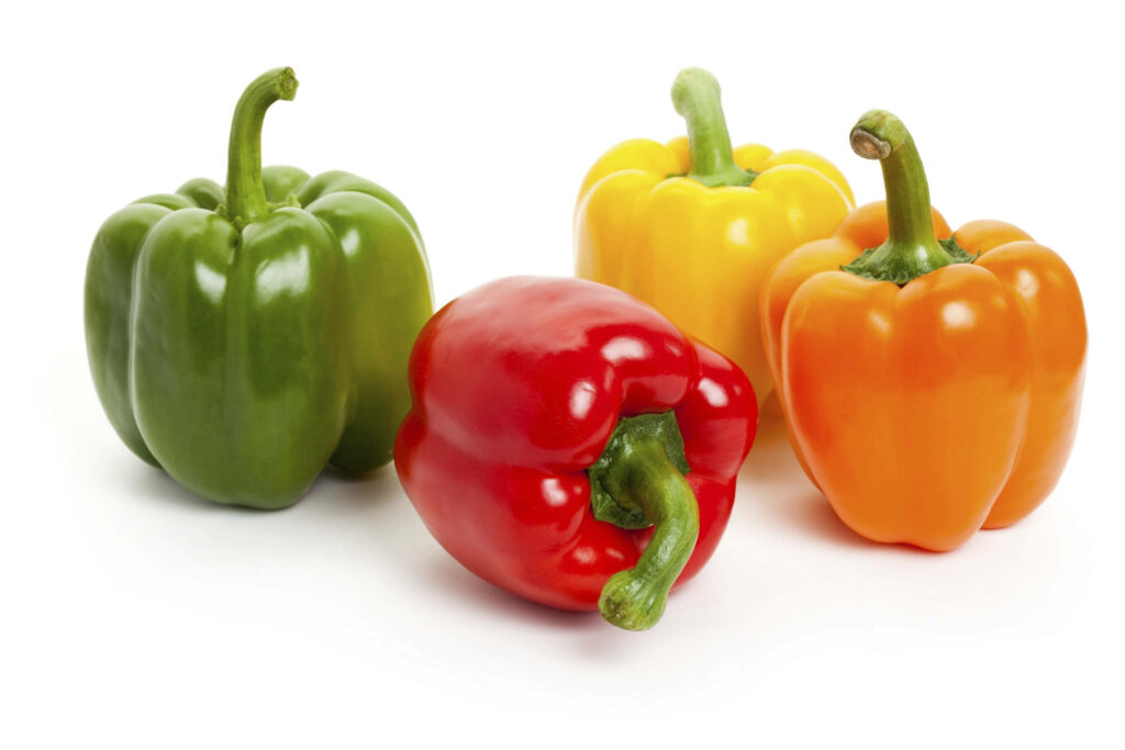 Vibrant wallpaper with fresh green red yellow and orange bell peppers on white background