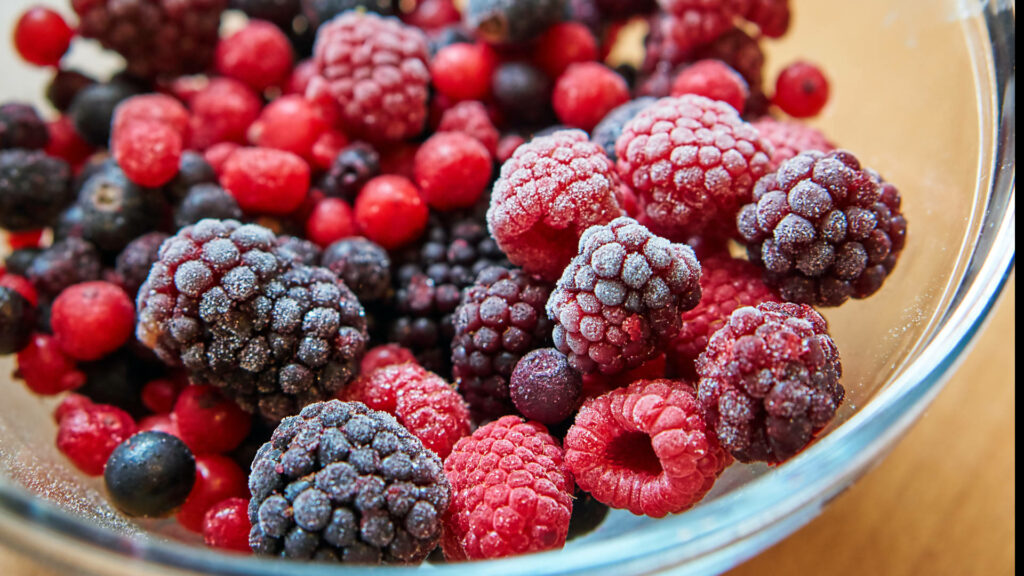 Close-up of fresh and frosted boysenberries raspberries and red currants in glass bowl wallpaper