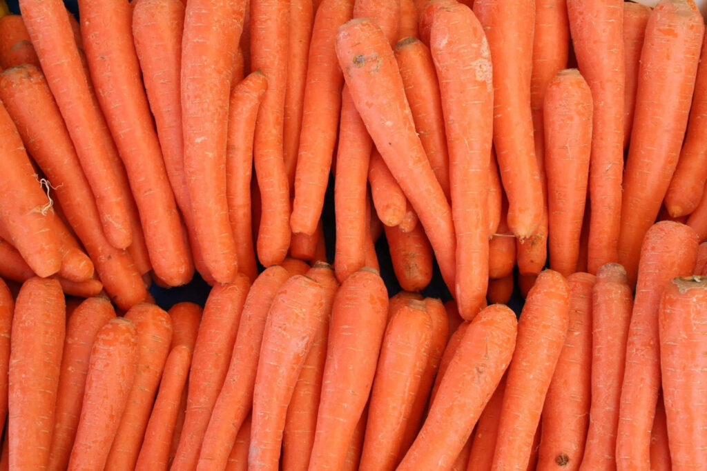 Close-up of fresh vibrant orange carrots showcasing natural texture and organic shapes wallpaper