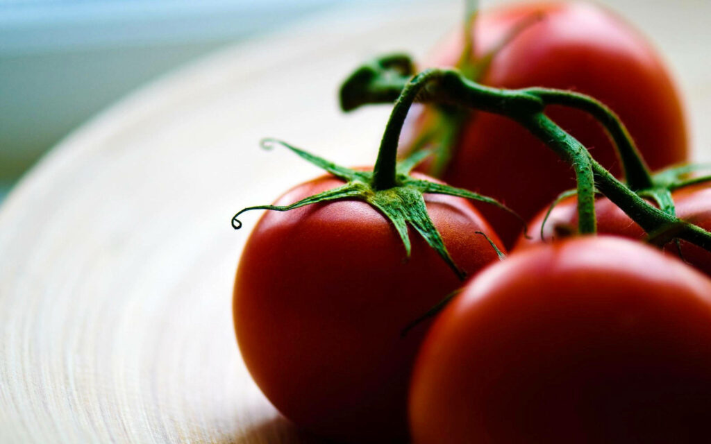 Fresh Red Tomatoes with Green Stems - Vibrant Wooden Table Wallpaper