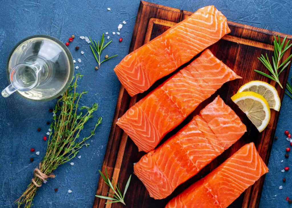 Vibrant Fresh Salmon Fillets with Lemon and Herbs on Blue Background Wallpaper