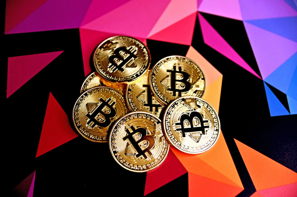 Vibrant geometric background with shiny gold Bitcoin coins symbolizing digital currency innovation Wallpaper